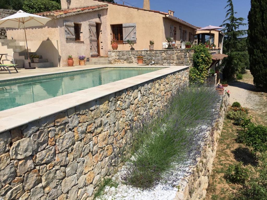 a stone wall around a swimming pool in front of a house at La Bergerie St Antoine in Spéracèdes