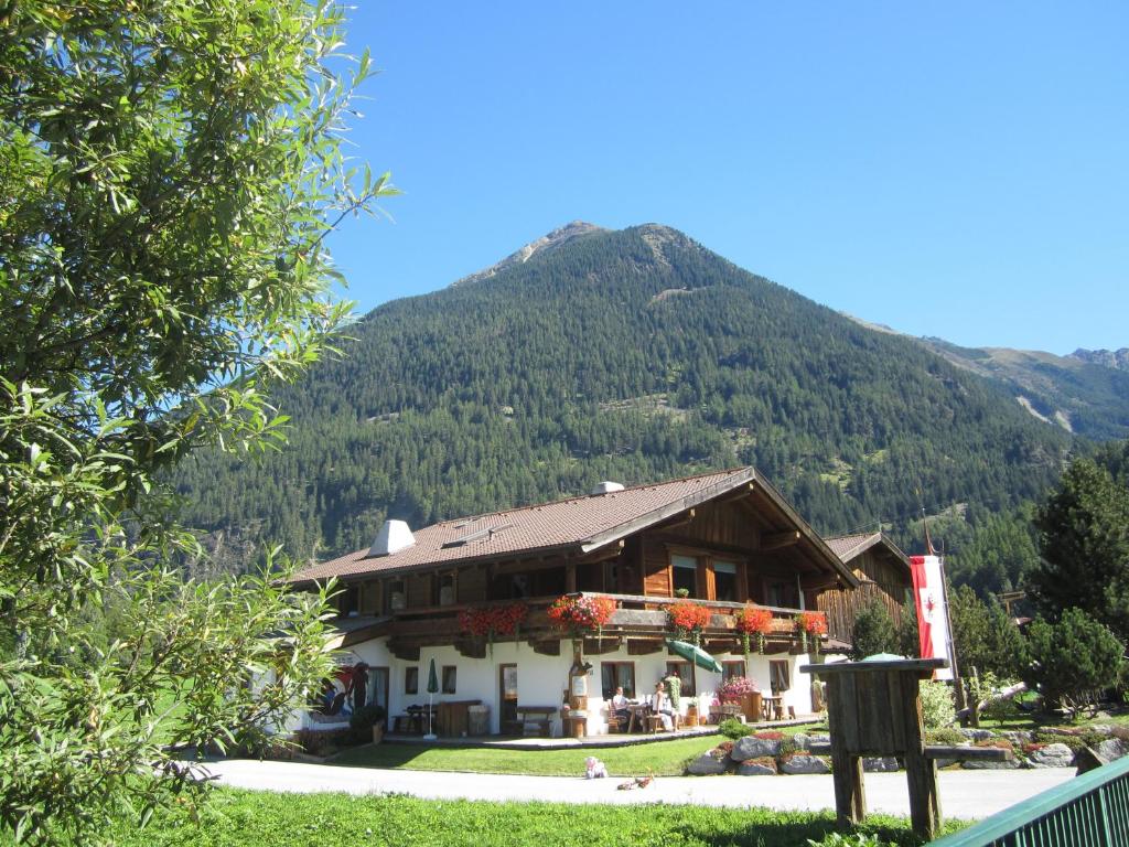 ein großes Gebäude mit einem Berg im Hintergrund in der Unterkunft Landsitz im Reitle in Längenfeld