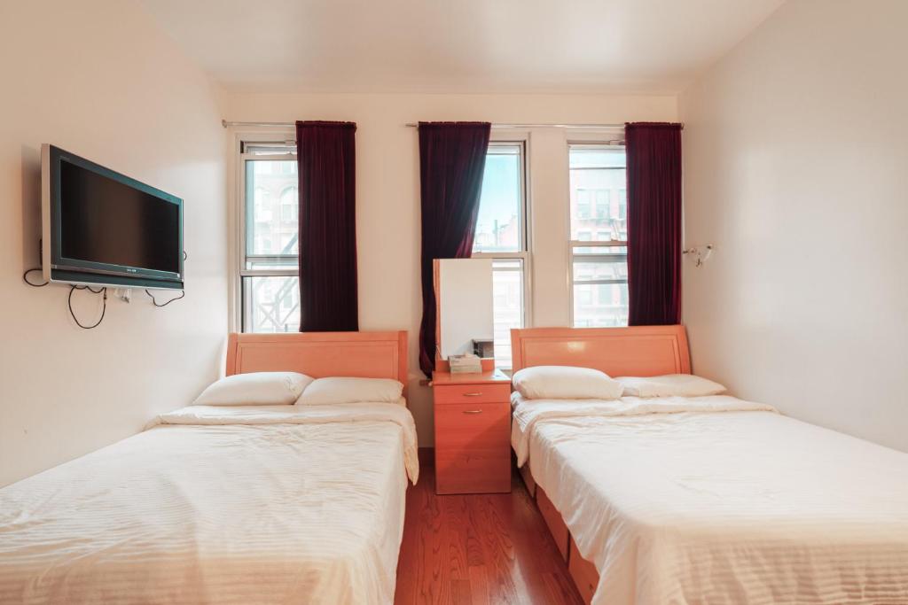 a room with two beds and a flat screen tv at U.S. Pacific Hotel in New York