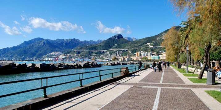 un gruppo di persone che camminano su un marciapiede vicino a un fiume di Il sorriso a Salerno