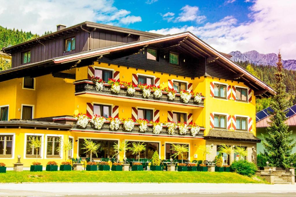 a yellow building with flowers on the balconies at Hotel Schladmingerhof in Schladming