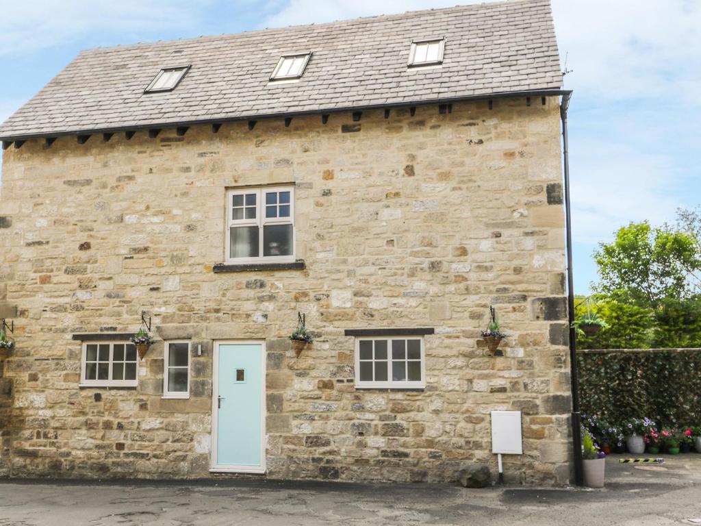 an old stone building with a white door at River Cottage in Morpeth