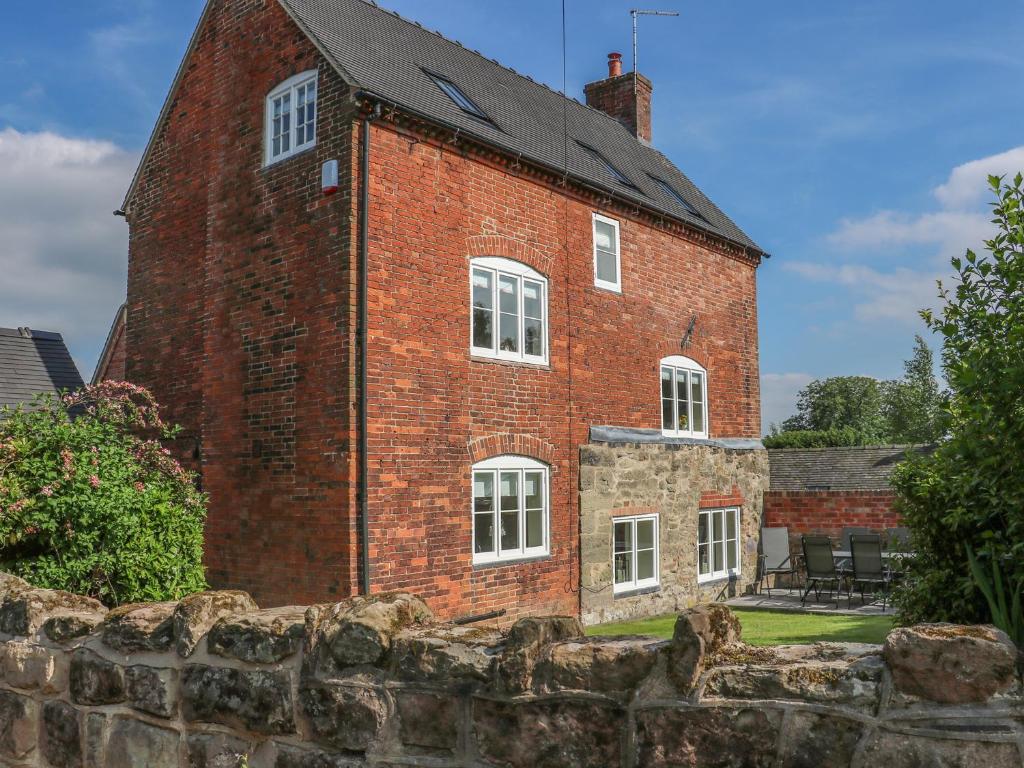 a large red brick building with white windows at Firtree Cottage in Ashby de la Zouch