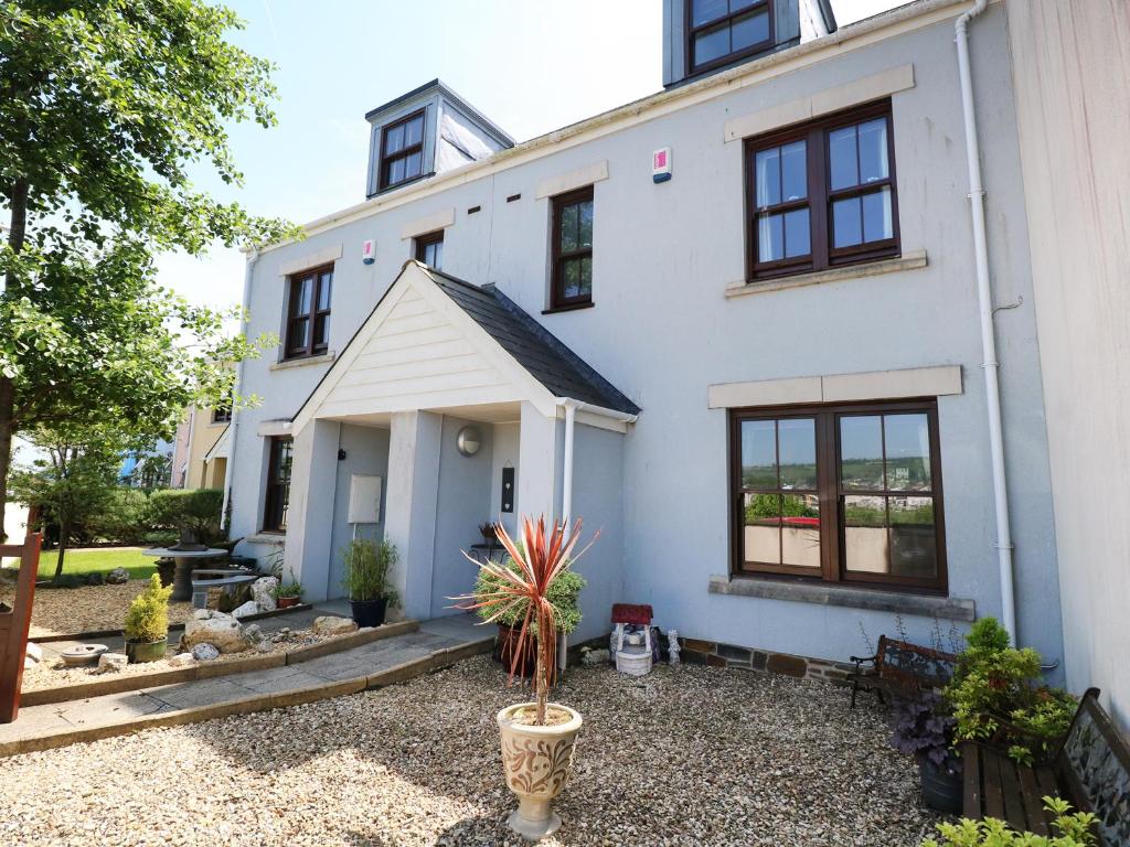 a white house with a potted plant in front of it at 5 Chandlers Yard in Burry Port