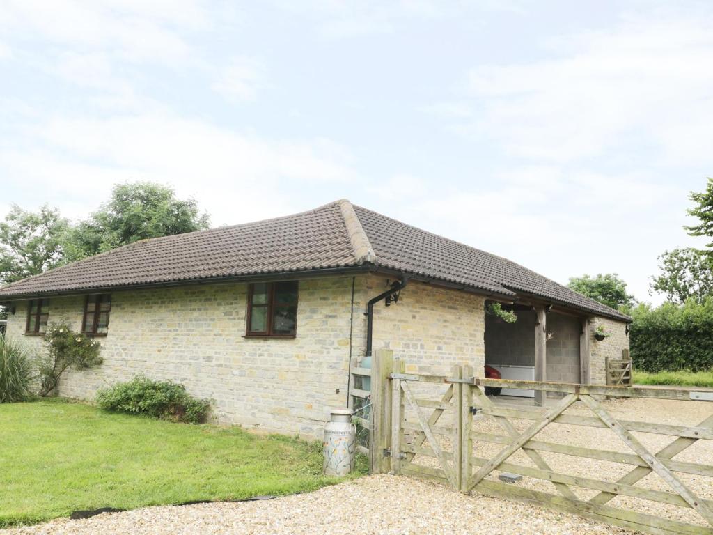a small white brick house with a wooden gate at The Old Goat Barn at Trout Cottage in Somerton