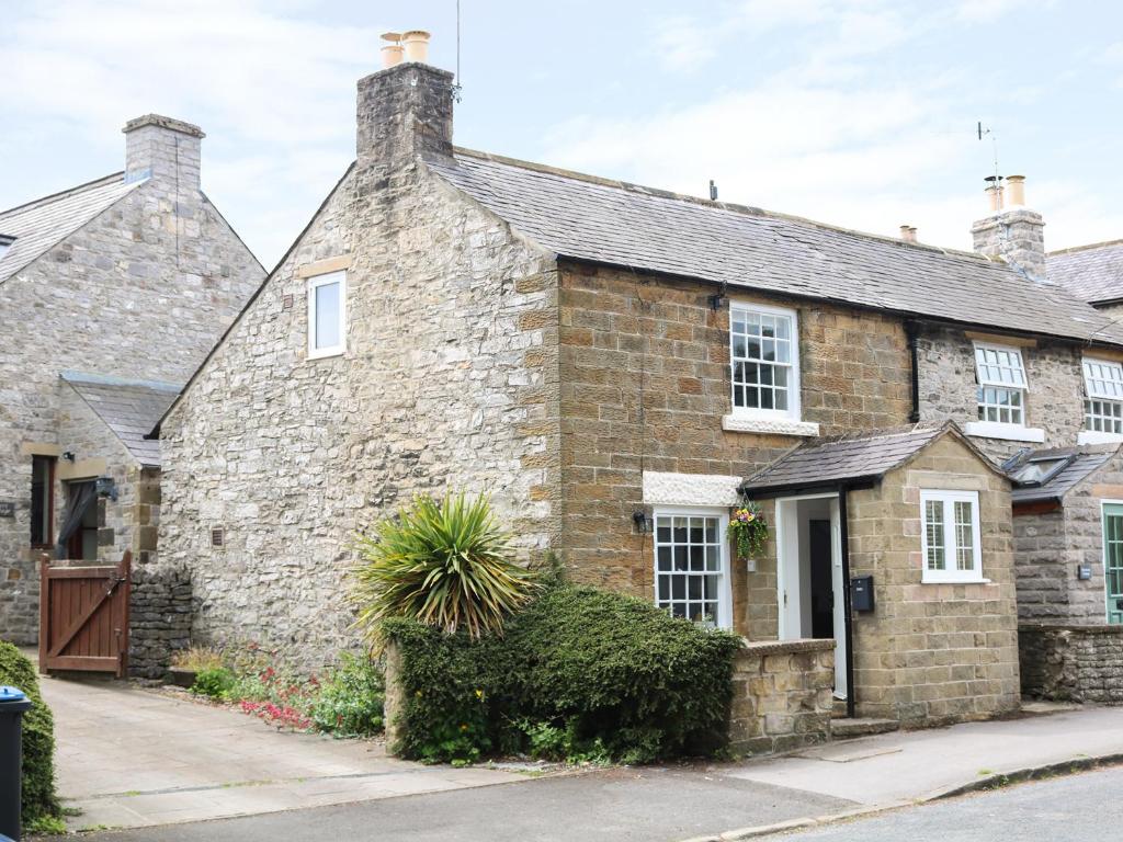 ein altes Steinhaus mit einer Pflanze davor in der Unterkunft Gritstone Cottage in Bakewell