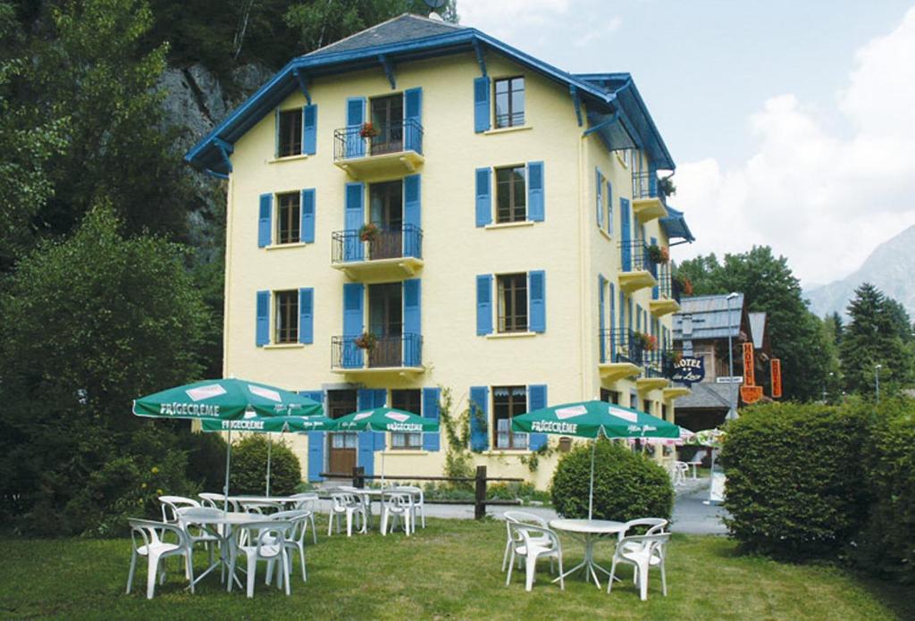 un grand bâtiment jaune avec des tables et des parasols verts dans l'établissement Hotel des Lacs, à Chamonix-Mont-Blanc