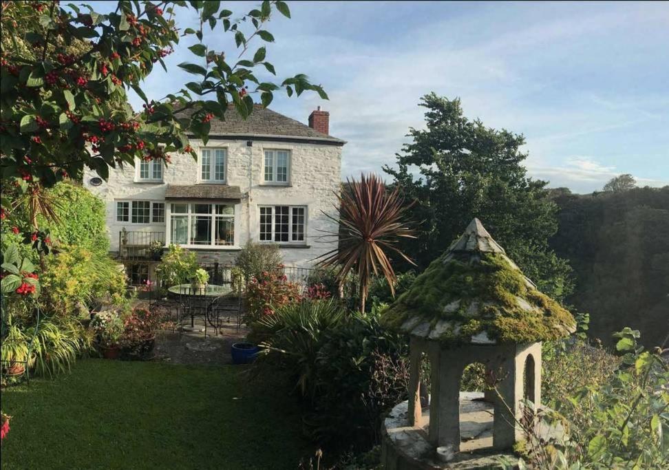 een groot wit huis met een tuinhuisje in de tuin bij Central Boscastle studio flat in Boscastle