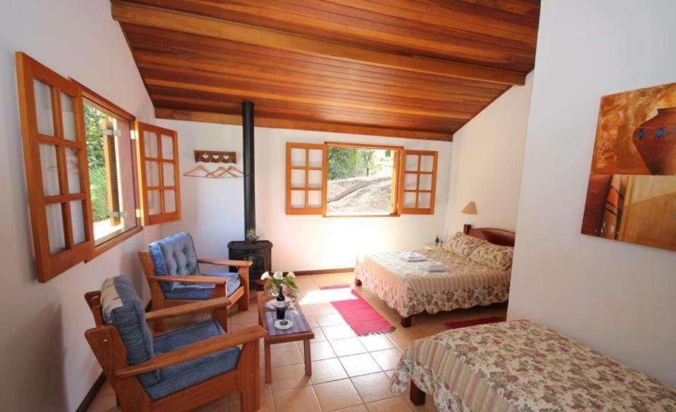 a bedroom with a bed and a bed and a chair at Pousada Kolibri in São Francisco Xavier