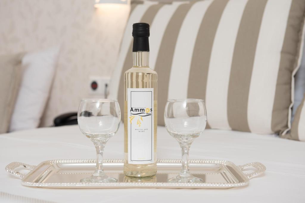 a bottle of wine and two wine glasses on a tray at Ammos Beach Seaside Luxury Suites Hotel in Olympic Beach