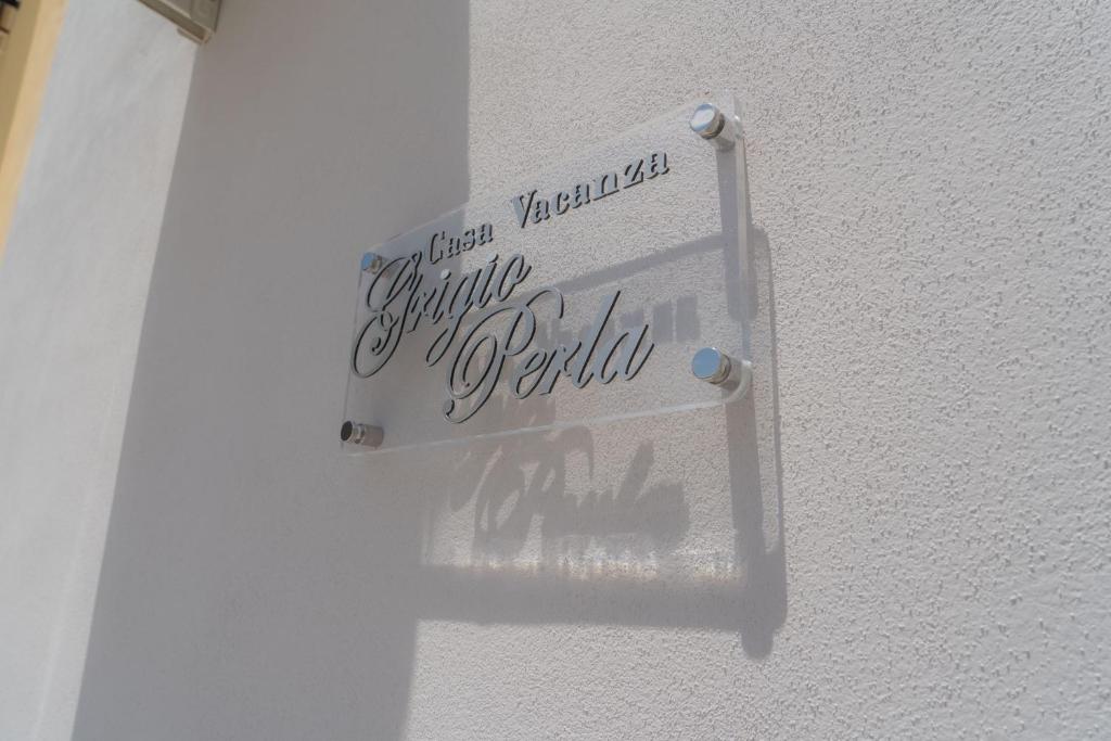 a sign on the side of a white wall at Casa vacanza “Grigio Perla” in Pachino