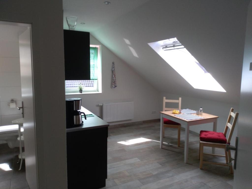 eine Küche mit einem Tisch und einem Dachfenster in der Unterkunft Pension Holmer Moorhof in Hartenholm