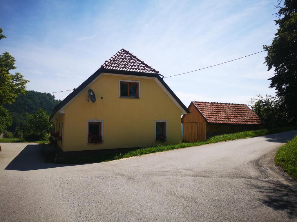 een geel huis met een rood dak naast een weg bij Robida in Vransko