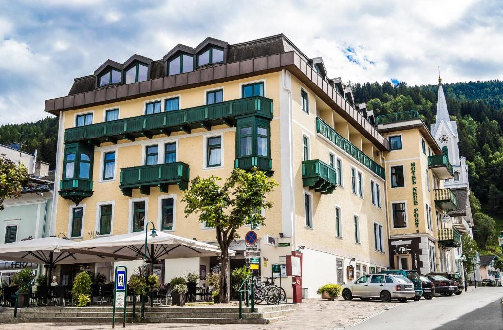 un bâtiment jaune avec des balcons verts dans une rue dans l'établissement Hotel Neue Post, à Schladming