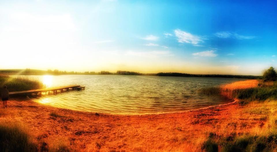 a view of a lake with the sun setting at Uroczysko Skomackie in Stare Juchy