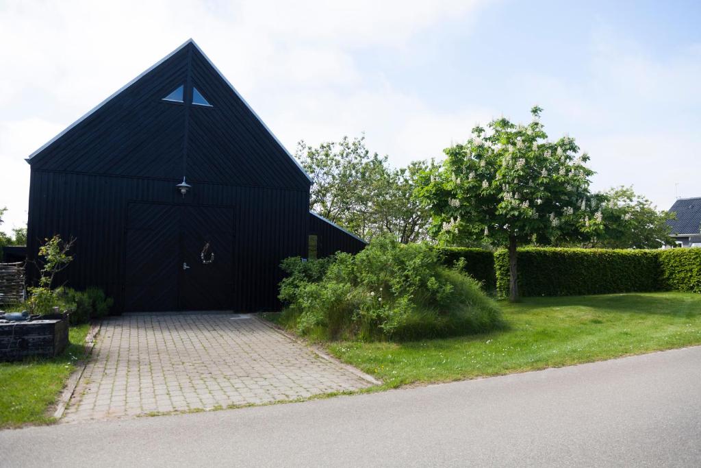 ein schwarzes Gebäude mit spitzem Dach im Hof in der Unterkunft Sdr. Bork in Hemmet