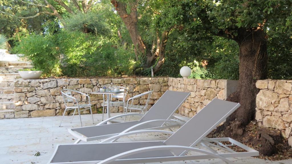 a group of chairs and a table and a stone wall at Le Castellas du Pic St Loup in Saint-Mathieu-de-Tréviers