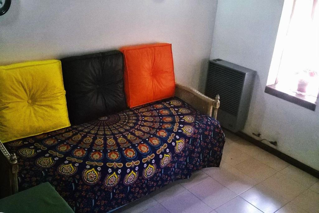 una cama con almohadas coloridas en una habitación en Departamento calido en San Martín de los Andes