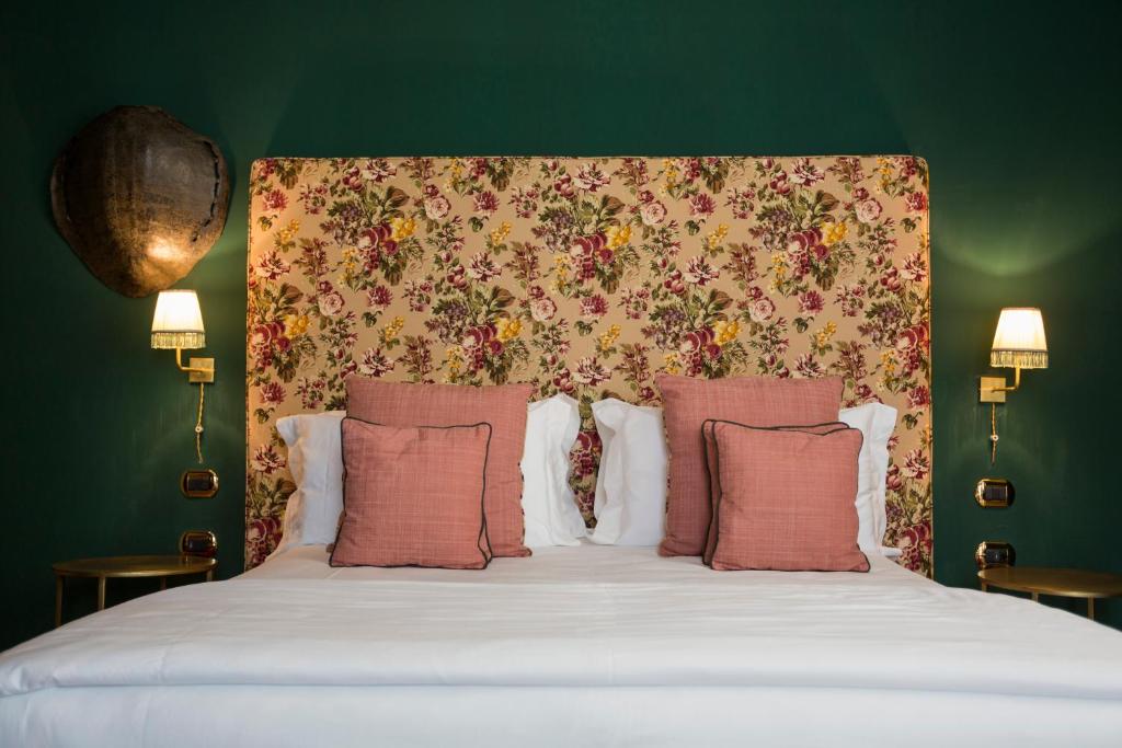una camera da letto con letto con testiera e cuscini floreali di Palazzo Presta a Gallipoli