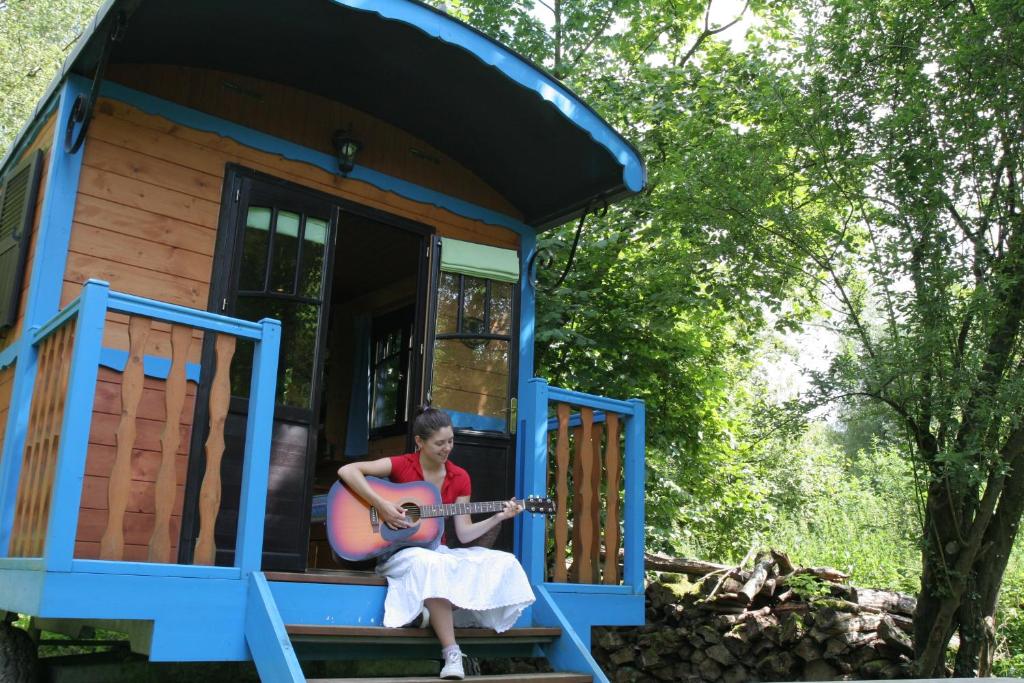 a woman playing a guitar in a tiny house at La Maison de l'Omignon in Vermand