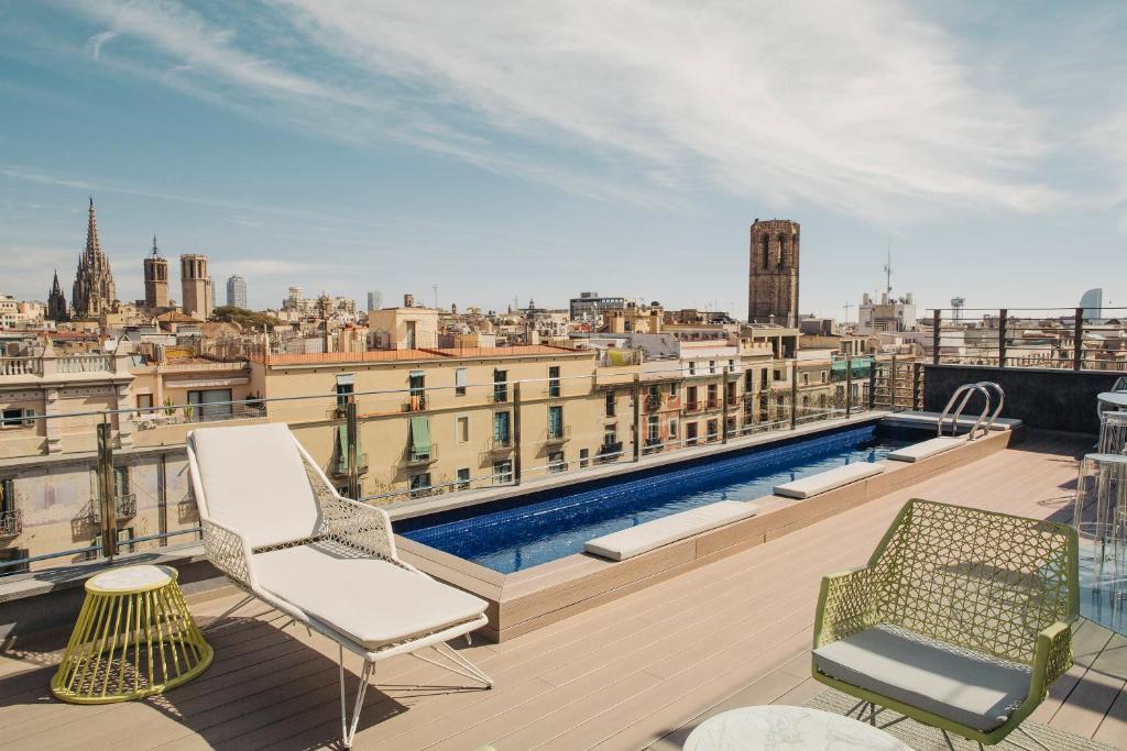 a beach with chairs, tables and a pool at Hotel Bagués, a Small Luxury Hotel of the World in Barcelona