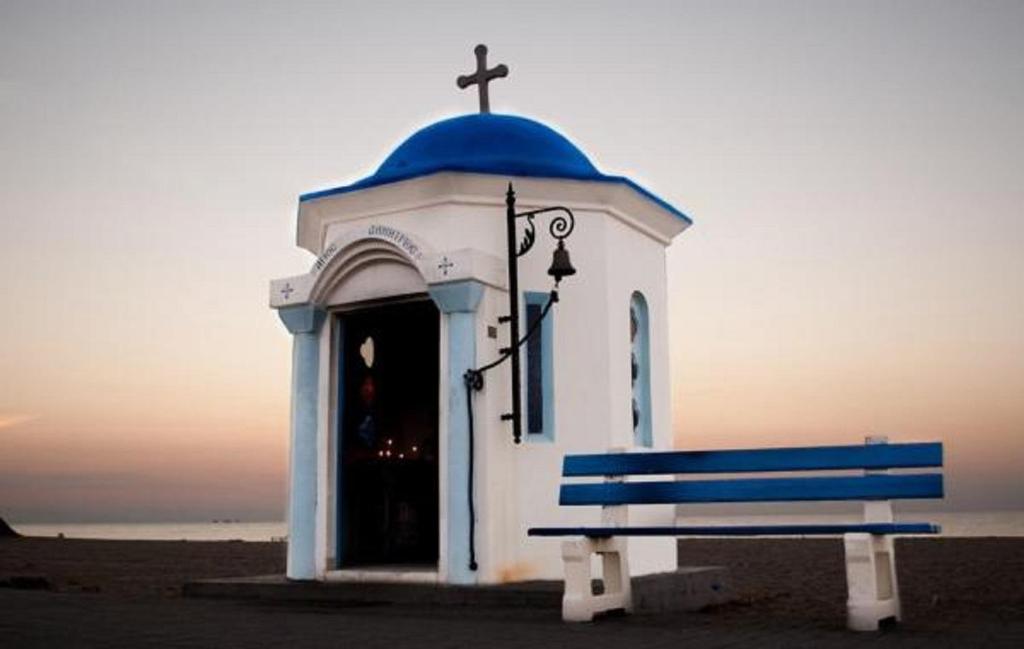a small chapel with a blue dome and a bench at Ammos Beach Seaside Luxury Suites Hotel in Olympic Beach