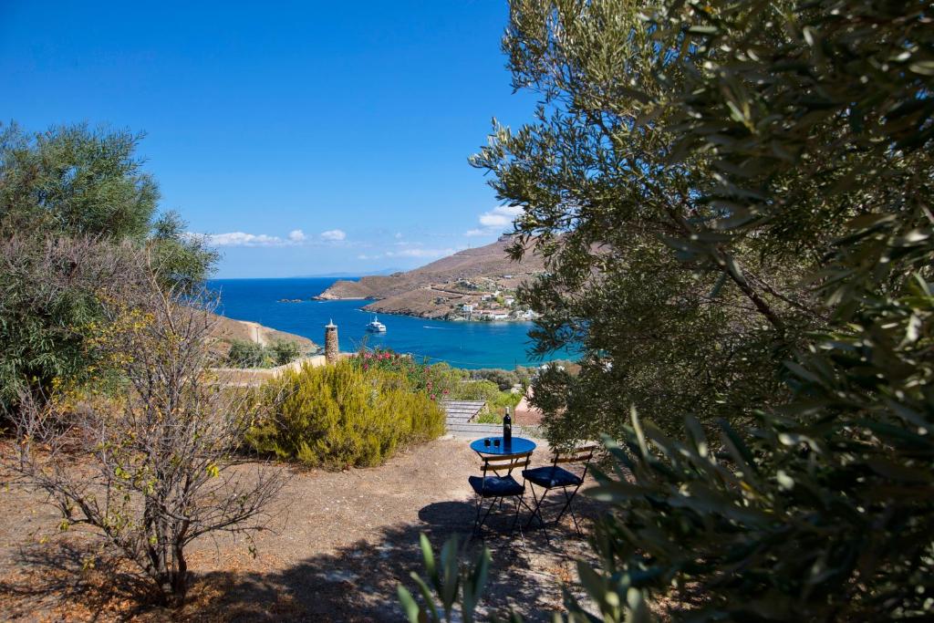 a picnic table and chairs on a hill overlooking the ocean at Stone house with a magical view in Otzias