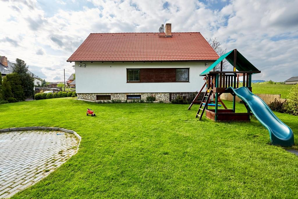 a yard with a playground with a slide and a house at Vila Poule in Bohutín