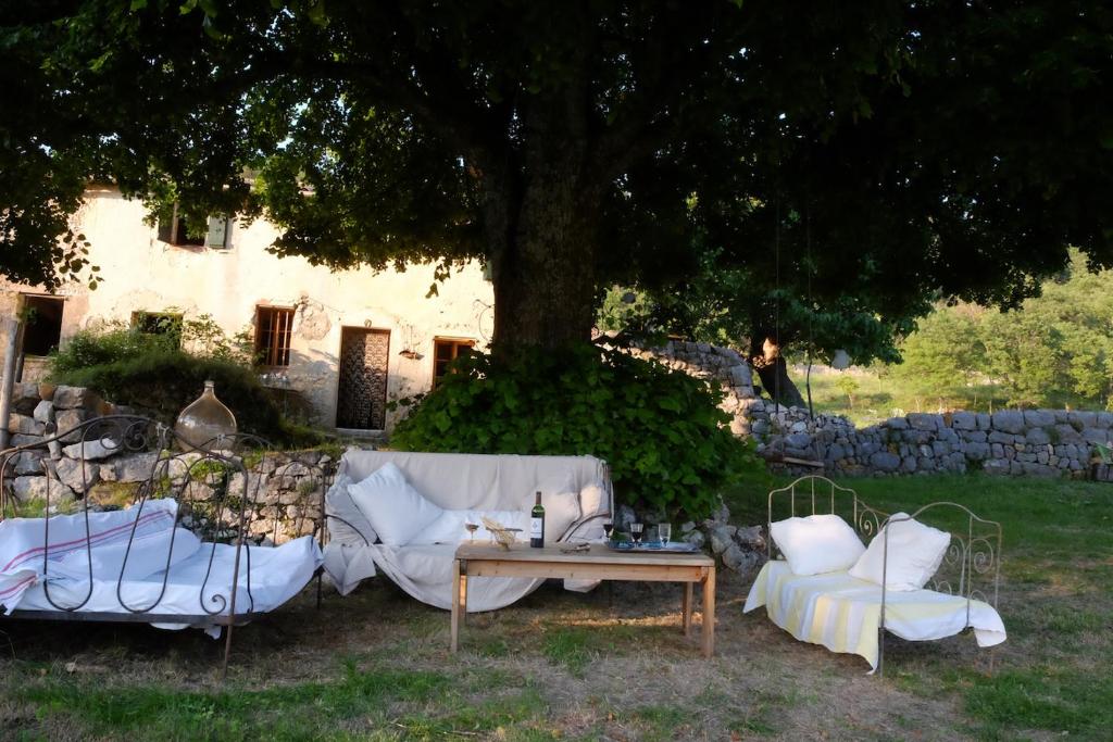 un divano bianco e due sedie sotto un albero di Maison Marthe a Coursegoules