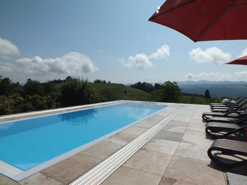 een zwembad met stoelen en een parasol bij Gästehaus Pension Bergwald in Scheidegg