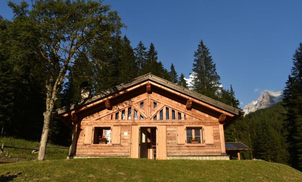 ein kleines Holzhaus auf einem Hügel mit Bäumen in der Unterkunft Chalet Brenta Dolomites in Madonna di Campiglio