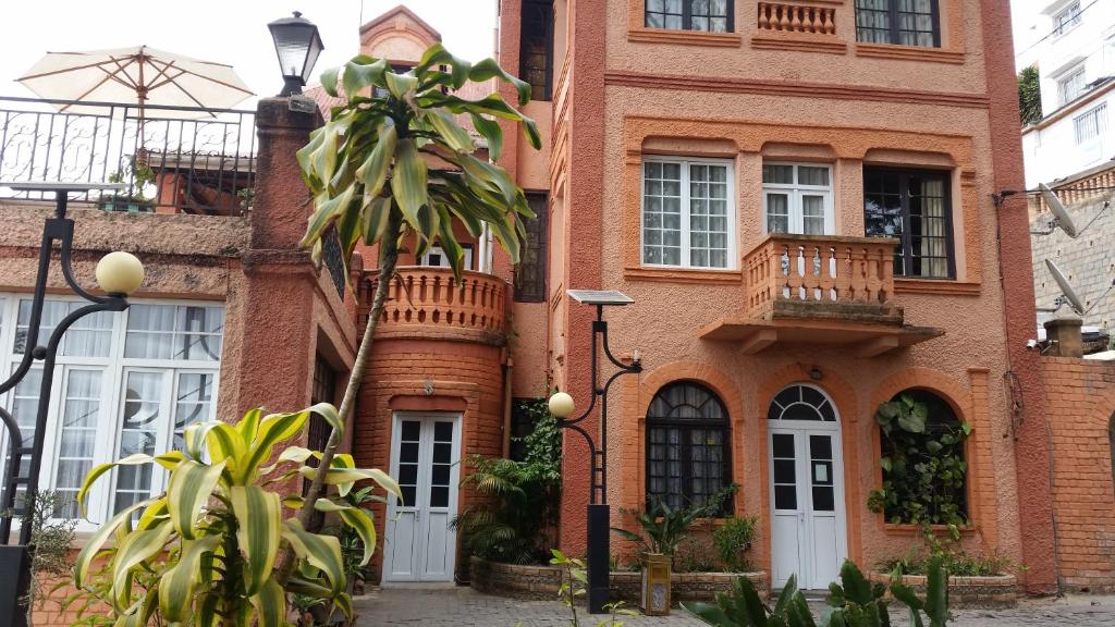 a brick house with a palm tree in front of it at Relais De La Haute Ville Tana in Antananarivo
