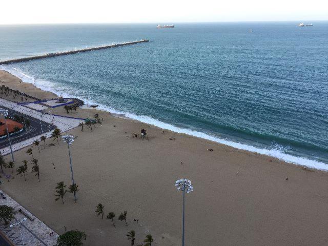 a beach with people on the sand and the ocean at Terraço do Atlântico in Fortaleza