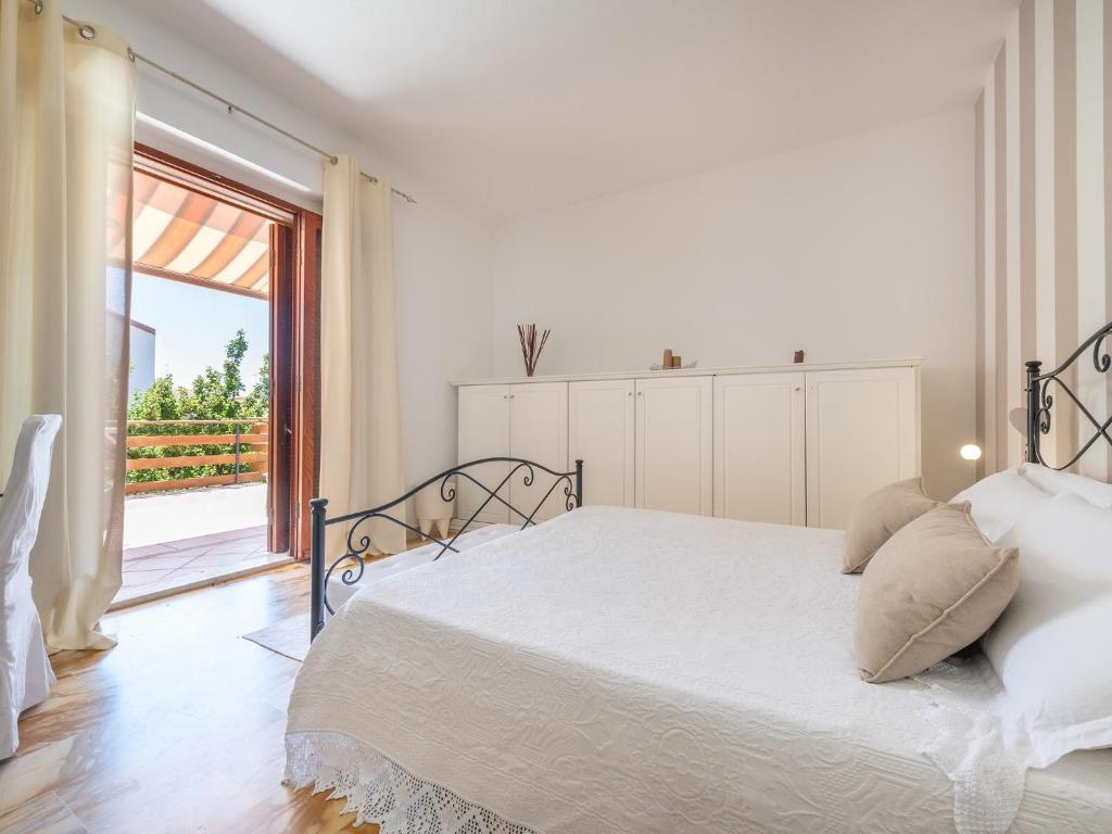 biała sypialnia z łóżkiem i dużym oknem w obiekcie Villa Iole w mieście Carloforte