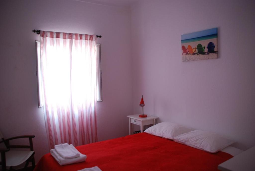 a bedroom with a red bed and a window at Casa Sobral in Vila Nova de Milfontes