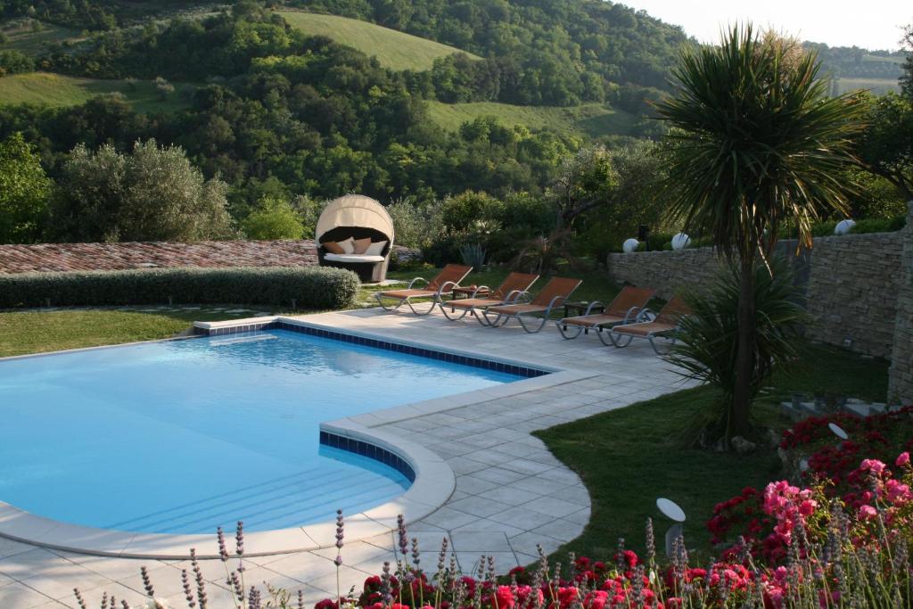 a swimming pool in a garden with a fire place at Relais Il Monticello in Montefiore Conca
