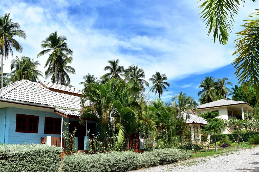 una casa sul lato di una strada con palme di Kate House Bangsaphan a Bang Saphan