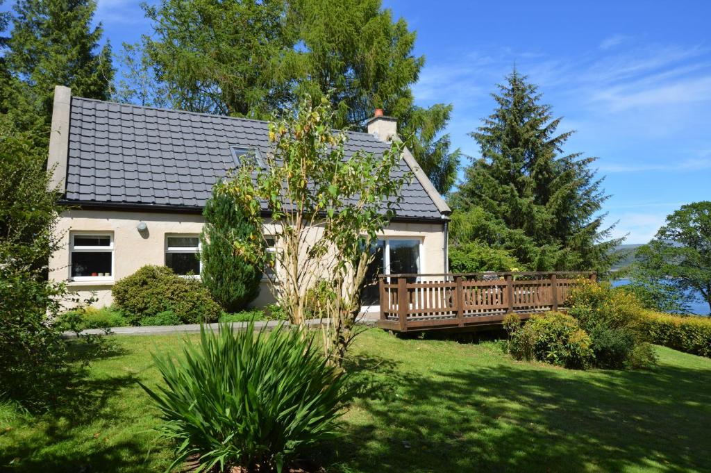 BlairmoreにあるAlder Cottageの庭に木製のデッキがある白い家
