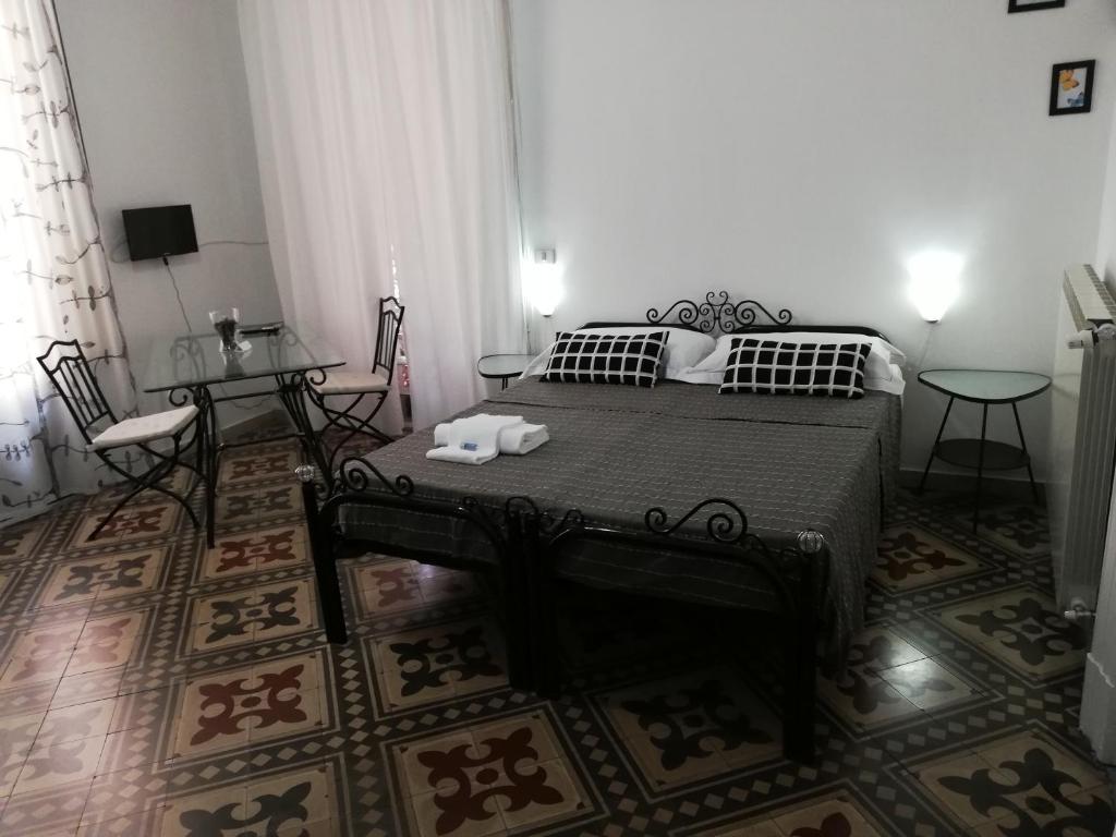 1 dormitorio con 1 cama, mesa y sillas en Aloi Rooms, en Catania