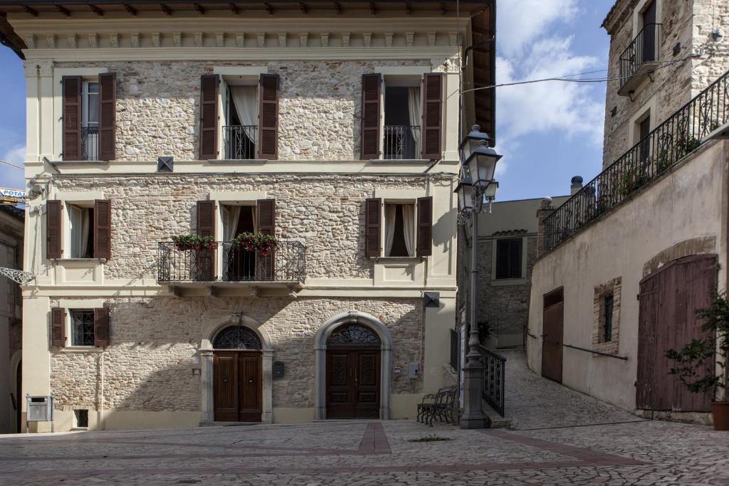 ein altes Steingebäude mit einer Tür und einem Balkon in der Unterkunft Dimora Il Palazzetto in Cugnoli