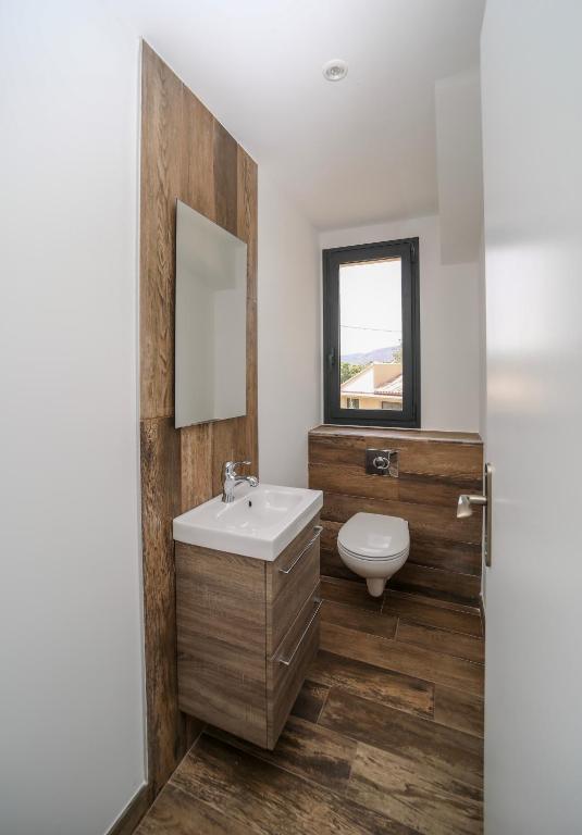 a bathroom with a sink and a toilet and a mirror at Hôtel confidentiel Le Grecale in Pianottoli-Caldarello