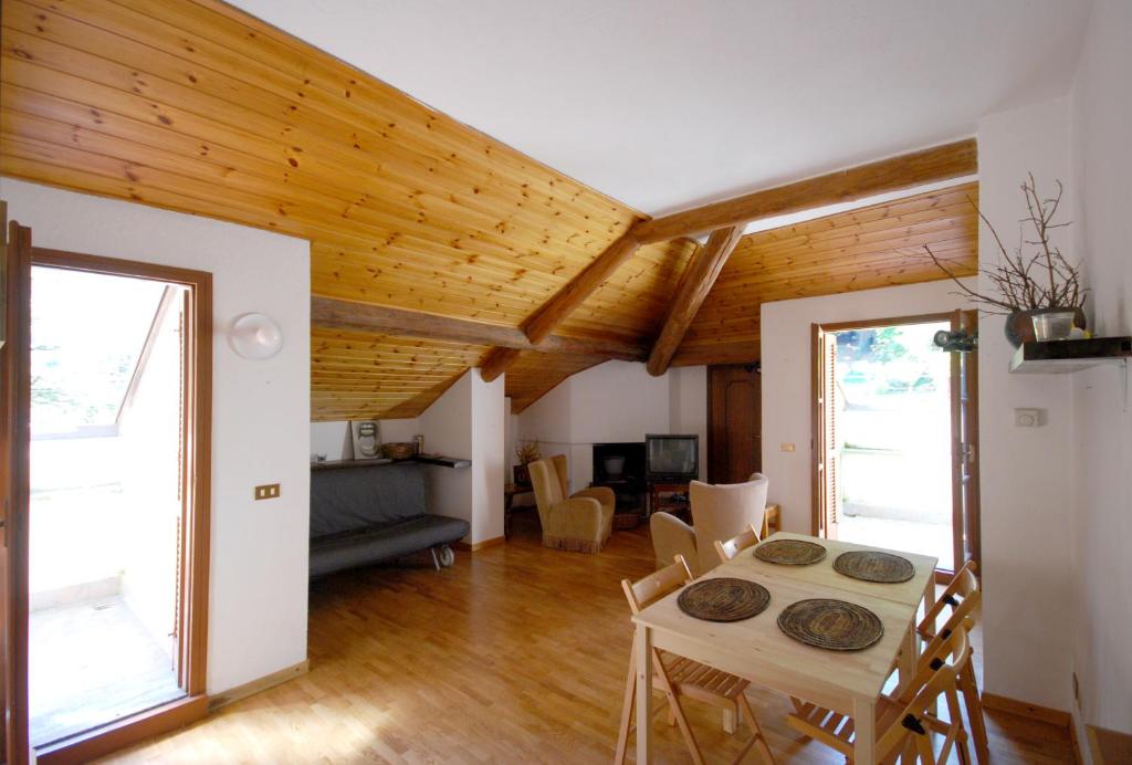 un soggiorno con tavolo, sedie e soffitti in legno di Bellagio Ghisallo Penthouse a Bellagio