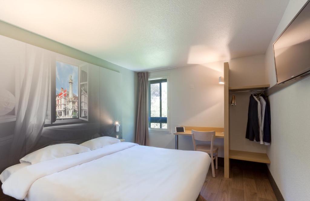 a hotel room with two beds and a window at B&B HOTEL CHAMBERY La Cassine in Chambéry