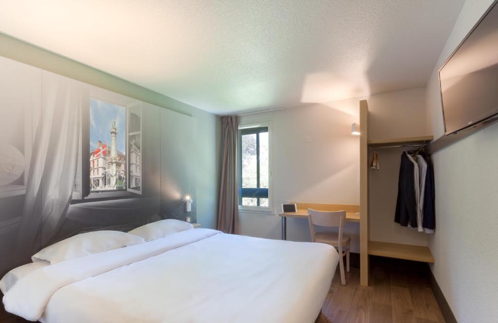 une chambre d'hôtel avec deux lits et une fenêtre dans l'établissement B&B HOTEL CHAMBERY La Cassine, à Chambéry