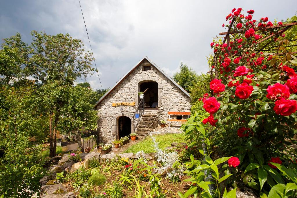 uma pequena igreja de pedra com rosas vermelhas em frente em Country House Atelier em Zvoneća