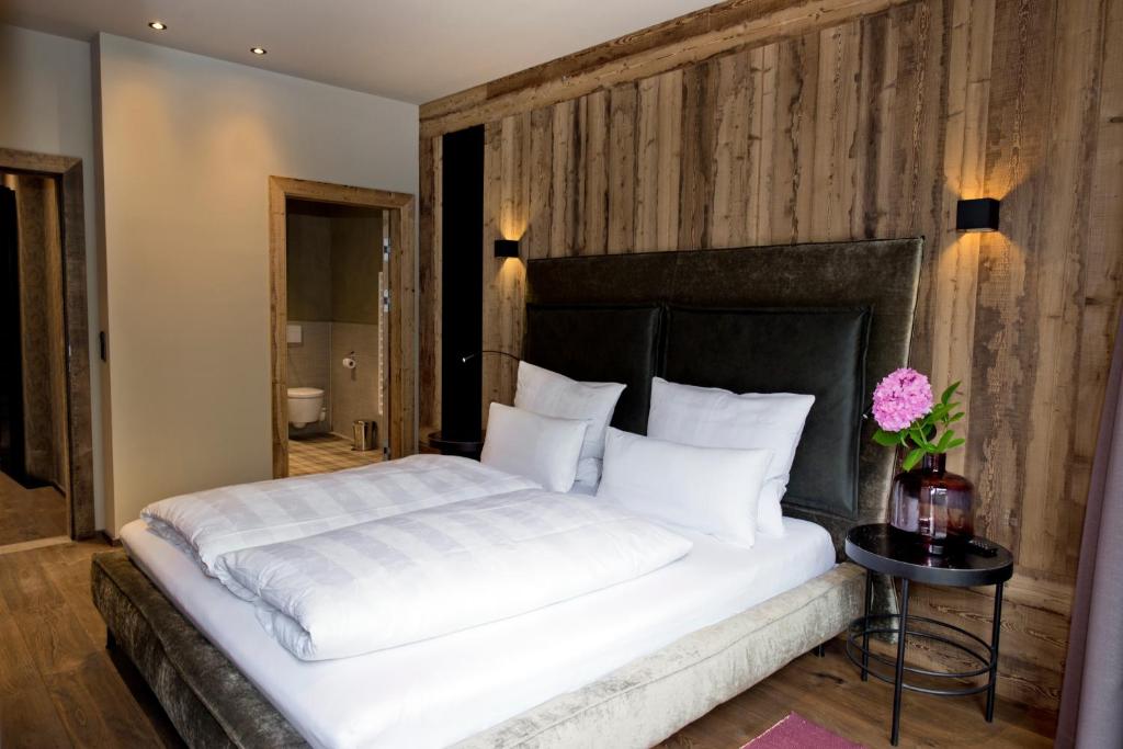 a bedroom with a white bed with a wooden wall at Postresidenz in Mayrhofen