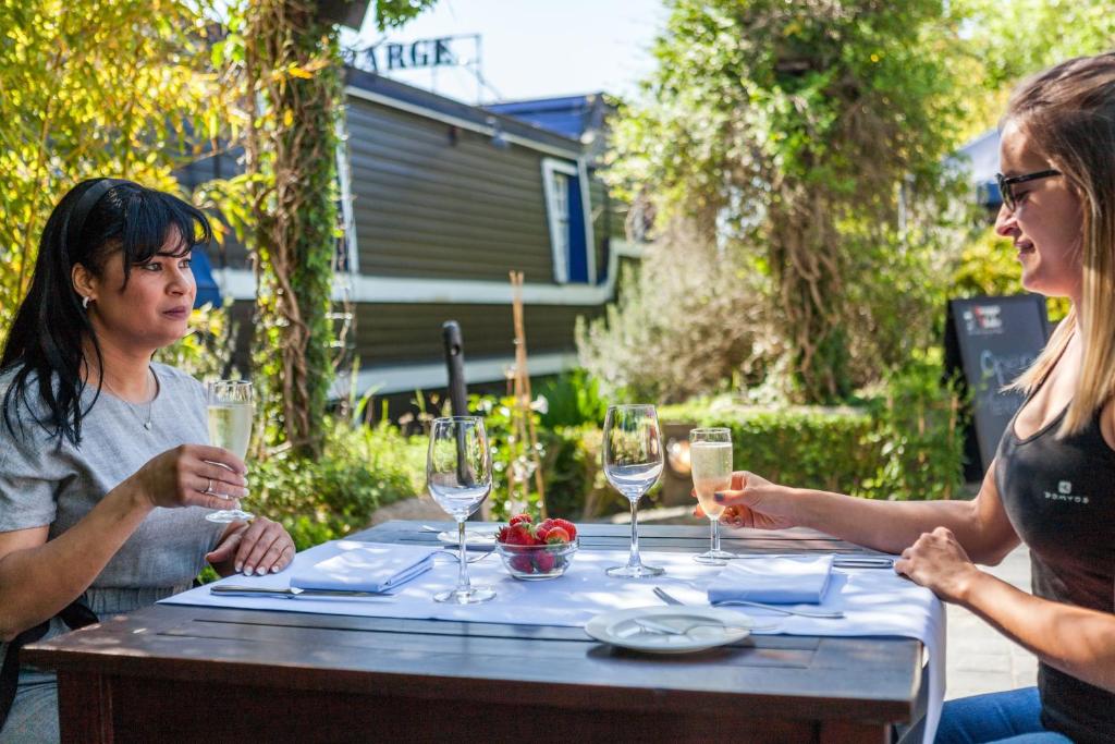 two women sitting at a table with wine glasses at Boat Hotel De Barge in Bruges