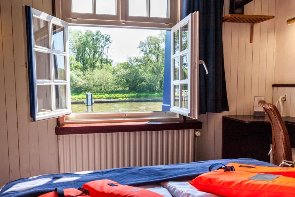 a room with a bed and a window with a view at Boat Hotel De Barge in Bruges