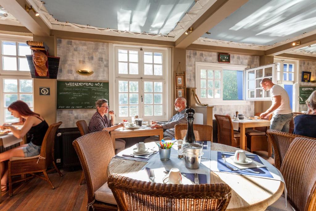 a group of people sitting at tables in a restaurant at Boat Hotel De Barge in Bruges