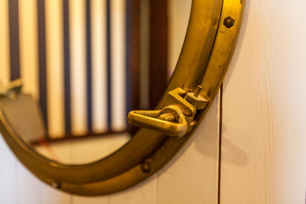a mirror with a brass handle on a wall at Boat Hotel De Barge in Bruges